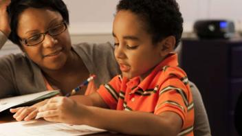 Mother and elementary school child looking at reading assignment together